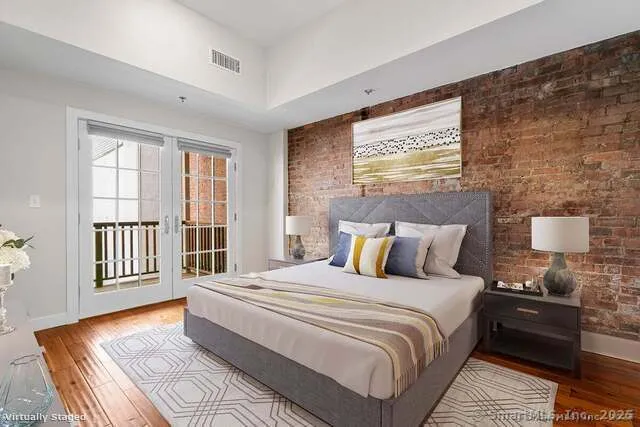 a spacious bedroom with a bed and wooden floor