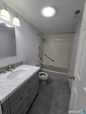 a bathroom with a granite countertop toilet a sink and a mirror