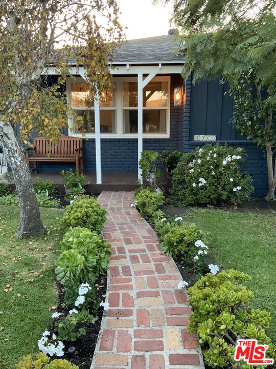 a front view of a house with a yard and potted plants