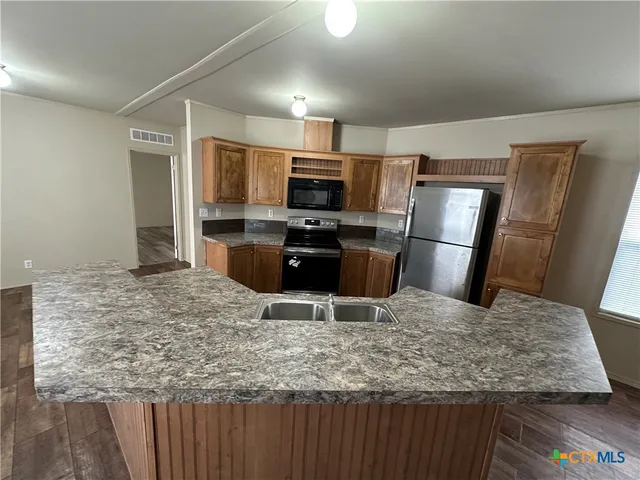 a kitchen with kitchen island a counter top space cabinets and stainless steel appliances