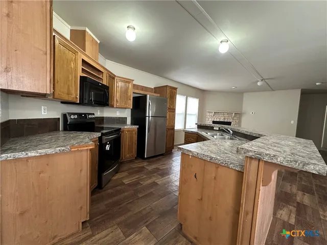 a kitchen with stainless steel appliances granite countertop a refrigerator a stove top oven a sink and dishwasher