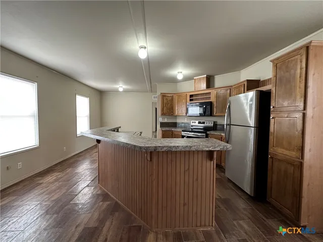 a kitchen with kitchen island a refrigerator sink and wooden cabinets