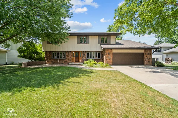 a front view of a house with a yard and trees