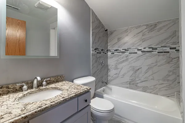 a bathroom with a granite countertop sink toilet and shower