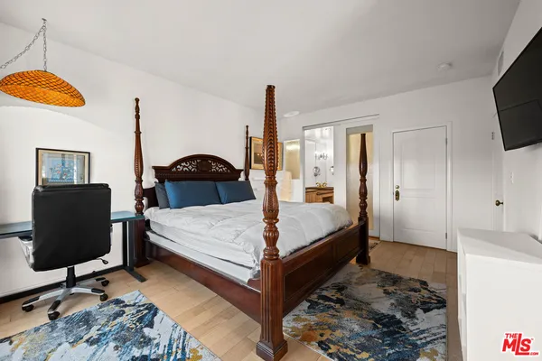 a bedroom with a bed a flat screen tv and dresser