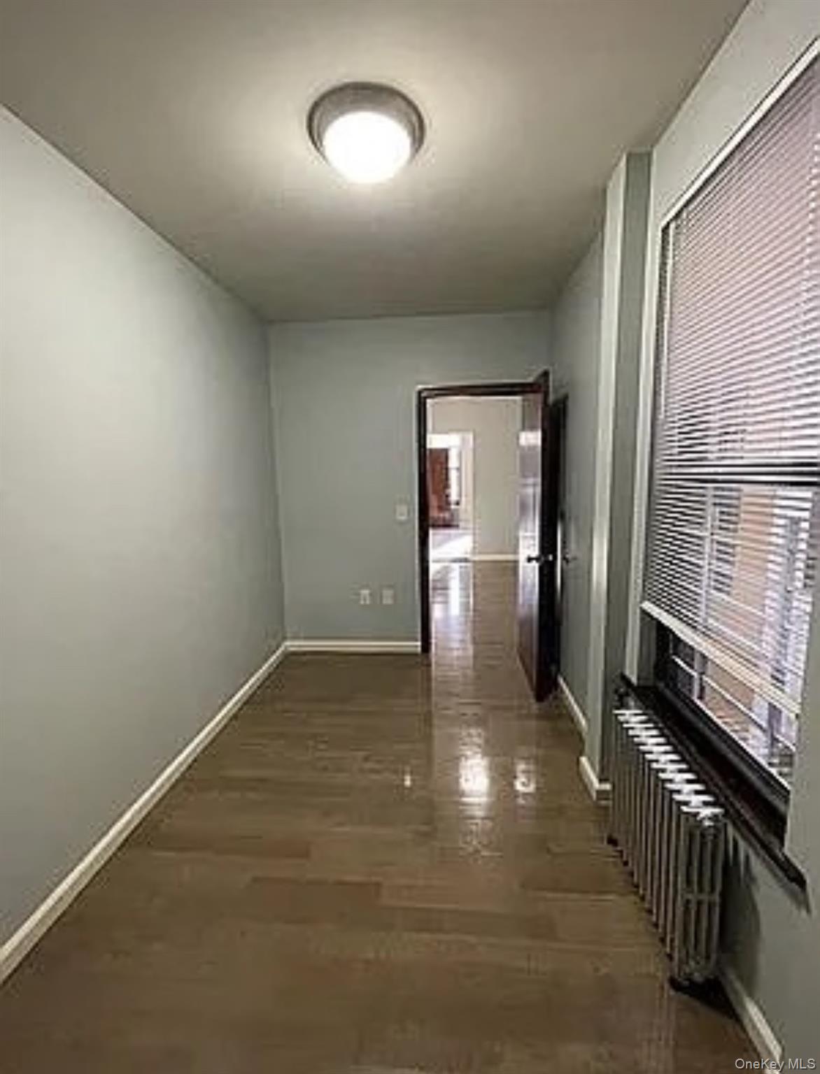 Undisclosed Address Queens, NY 11385 - Photo 4 of 6 an empty room with wooden floor mirror and windows