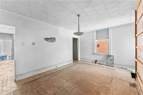 a view of an empty room with window and wooden floor
