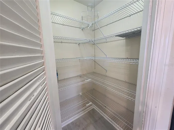 a walk in closet with wooden floor