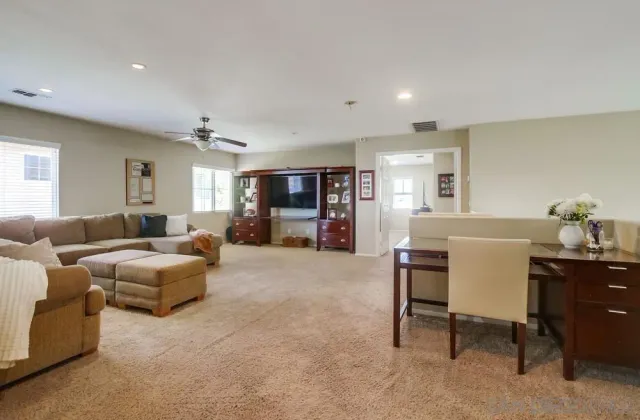 a living room with furniture and a dining table with kitchen appliances