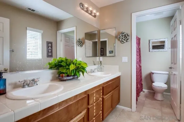 a bathroom with a granite countertop sink a toilet a mirror and shower