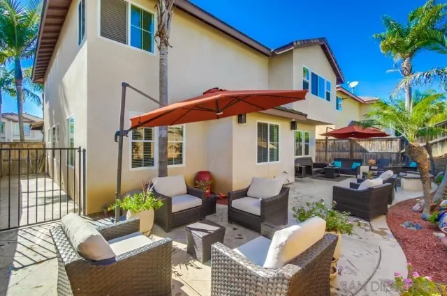 a view of a patio with couches table and chairs under an umbrella