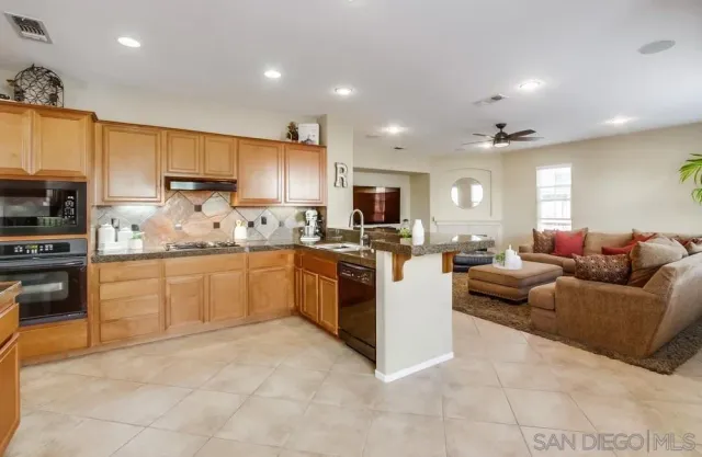 a large white kitchen with a stove a sink a refrigerator and a dining table with wooden floor