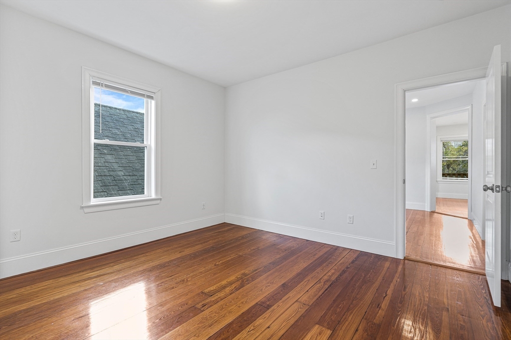 307 Hancock Street, Unit 3 Boston, MA 02125 - Photo 14 of 25 a view of an empty room with wooden floor and a window