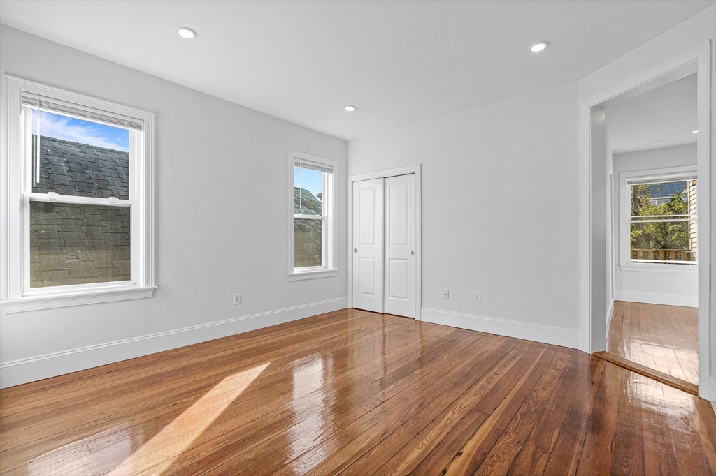 307 Hancock Street, Unit 3 Boston, MA 02125 - Photo 16 of 25 a view of an empty room with wooden floor and a window