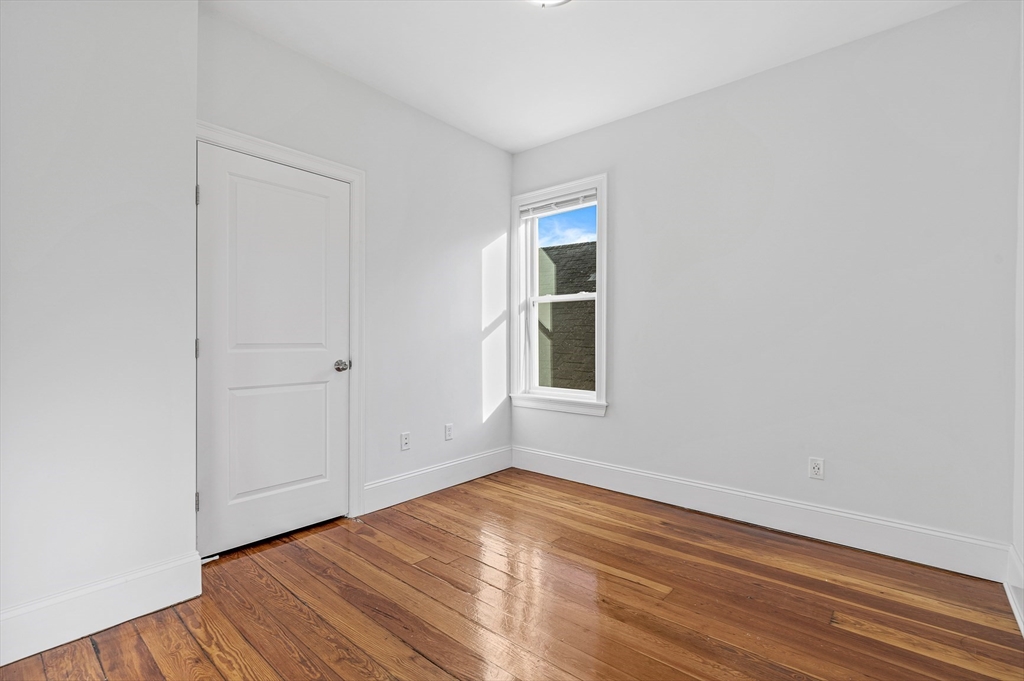 307 Hancock Street, Unit 3 Boston, MA 02125 - Photo 20 of 25 a view of an empty room with wooden floor and a window