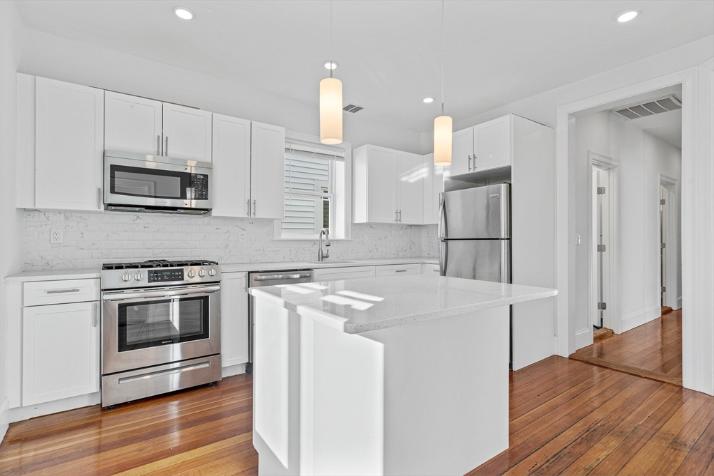 307 Hancock Street, Unit 3 Boston, MA 02125 - Photo 2 of 25 a kitchen with stainless steel appliances granite countertop a stove a refrigerator and a microwave