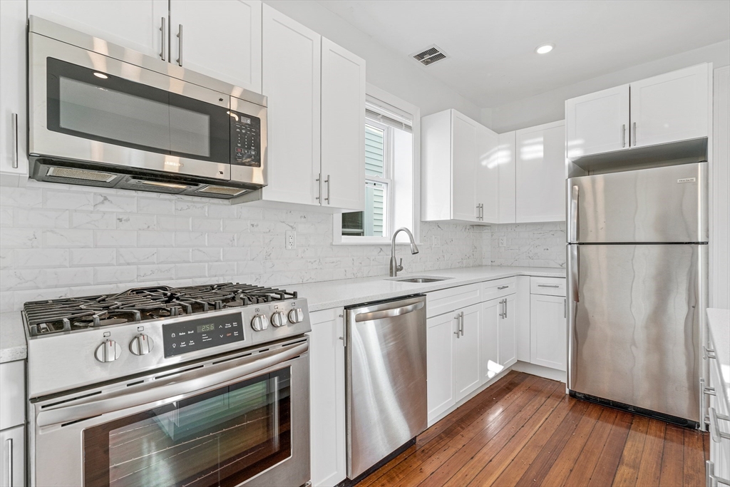 307 Hancock Street, Unit 3 Boston, MA 02125 - Photo 3 of 25 a kitchen with cabinets stainless steel appliances a sink and wooden floor