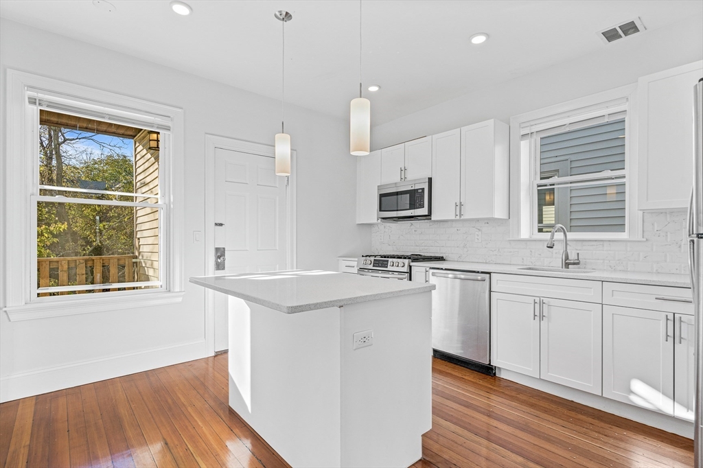 307 Hancock Street, Unit 3 Boston, MA 02125 - Photo 6 of 25 a kitchen with granite countertop cabinets stainless steel appliances a sink and a window