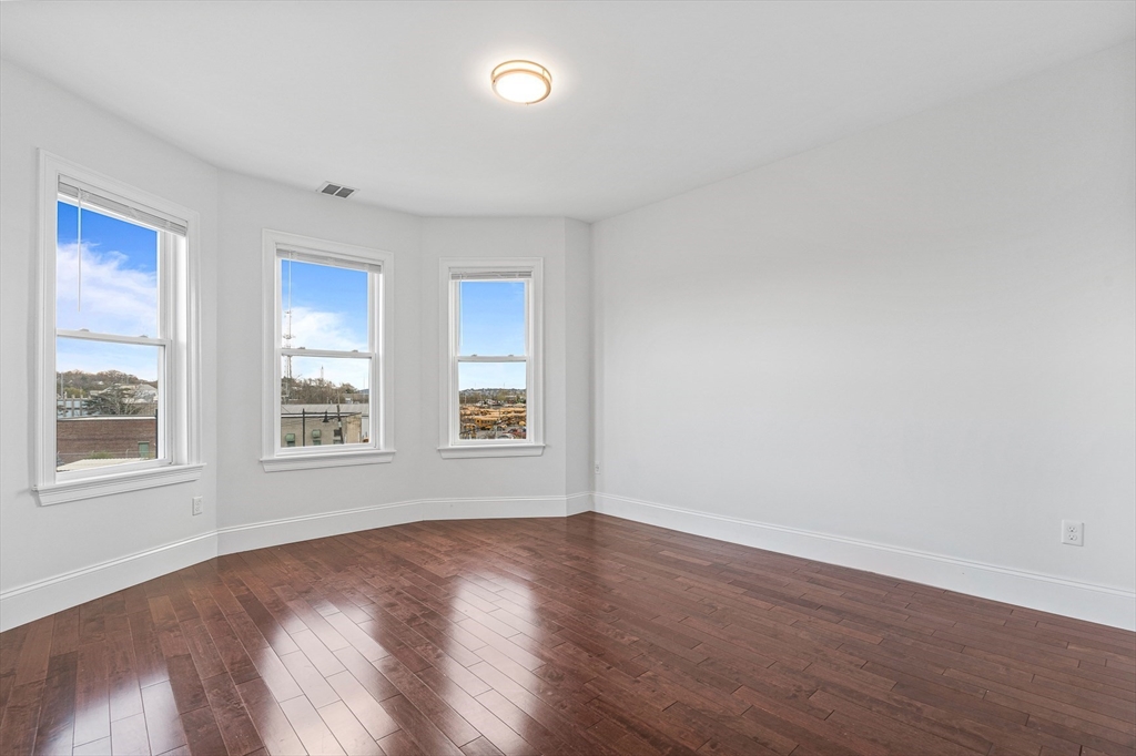 307 Hancock Street, Unit 3 Boston, MA 02125 - Photo 7 of 25 an empty room with wooden floor and windows