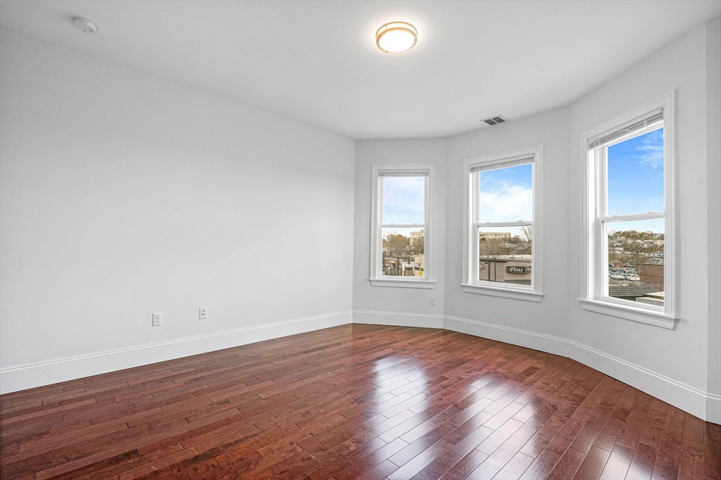 307 Hancock Street, Unit 3 Boston, MA 02125 - Photo 8 of 25 an empty room with wooden floor and windows