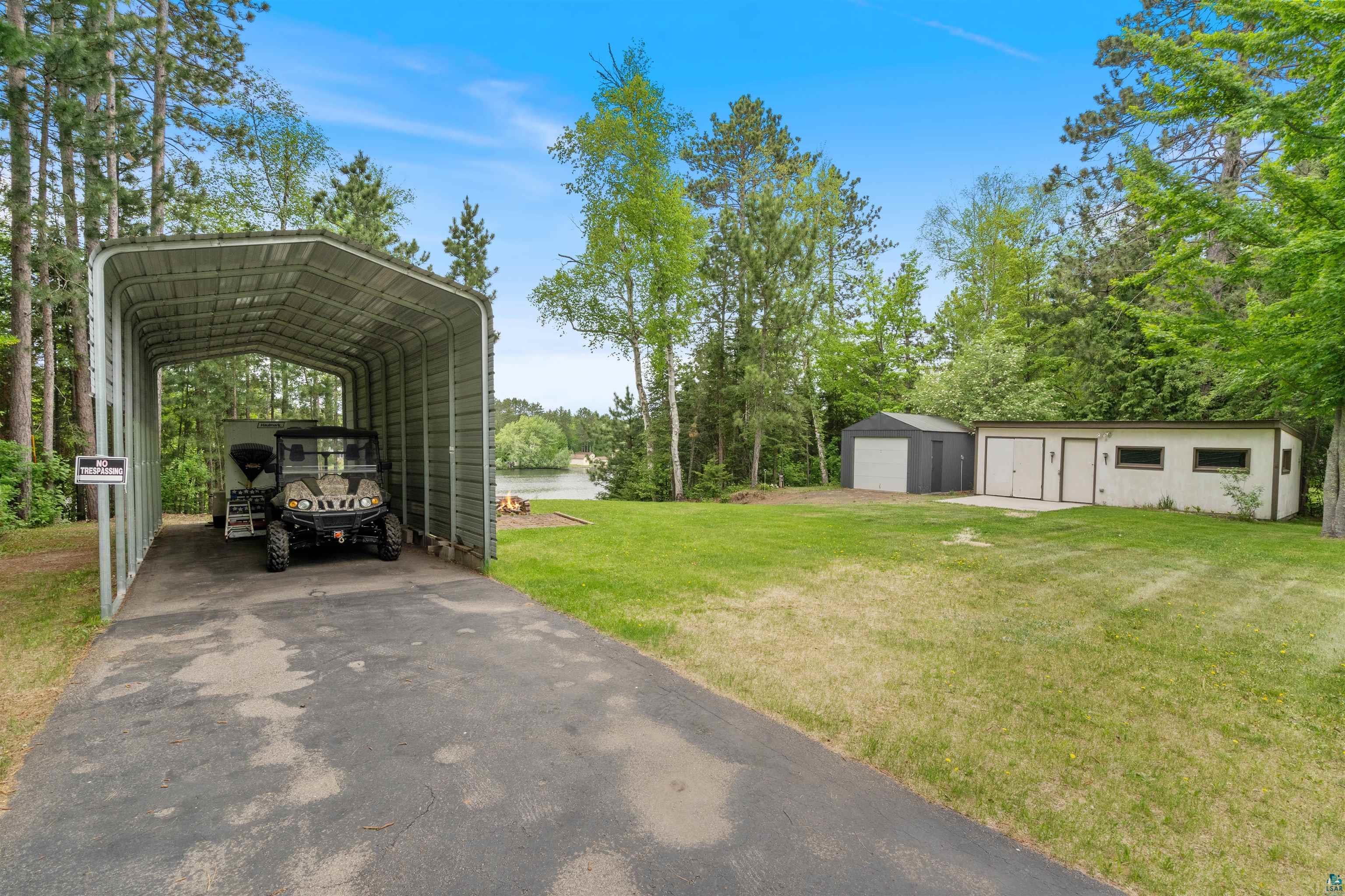 3975 Long Lake Shores Road Eveleth, MN 55734 - Photo 37 of 52 Paved driveway leading to a metal RV carport, a workshop, an additional storage shed