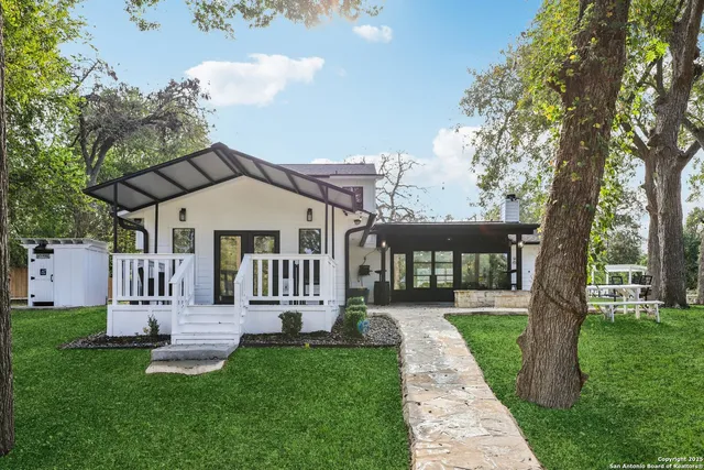 a front view of a house with a garden and trees