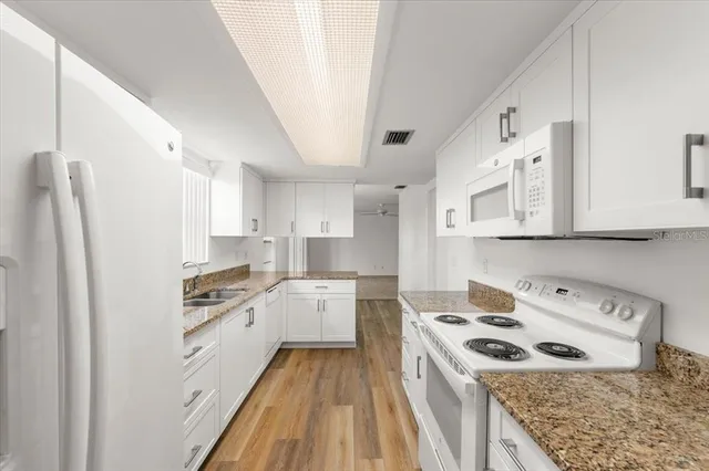 a kitchen that has a lot of cabinets and wooden floor