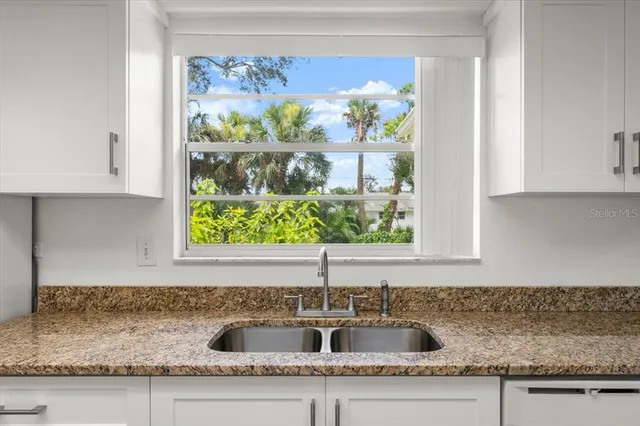 a kitchen with granite countertop a sink a stove and cabinets