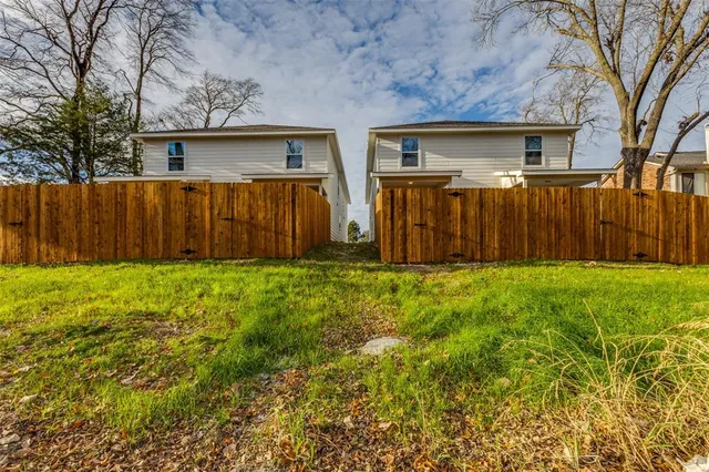 a view of backyard with large trees and wooden fence