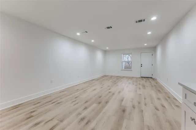 an empty room with wooden floor and natural light