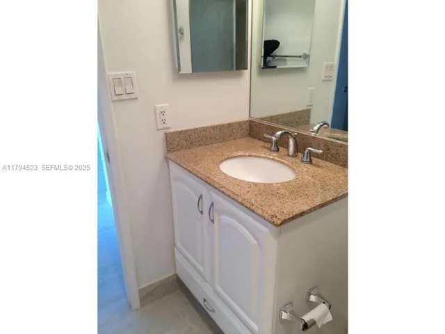 a bathroom with a granite countertop sink and a mirror