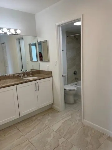 a spacious bathroom with a granite countertop sink a toilet and a mirror