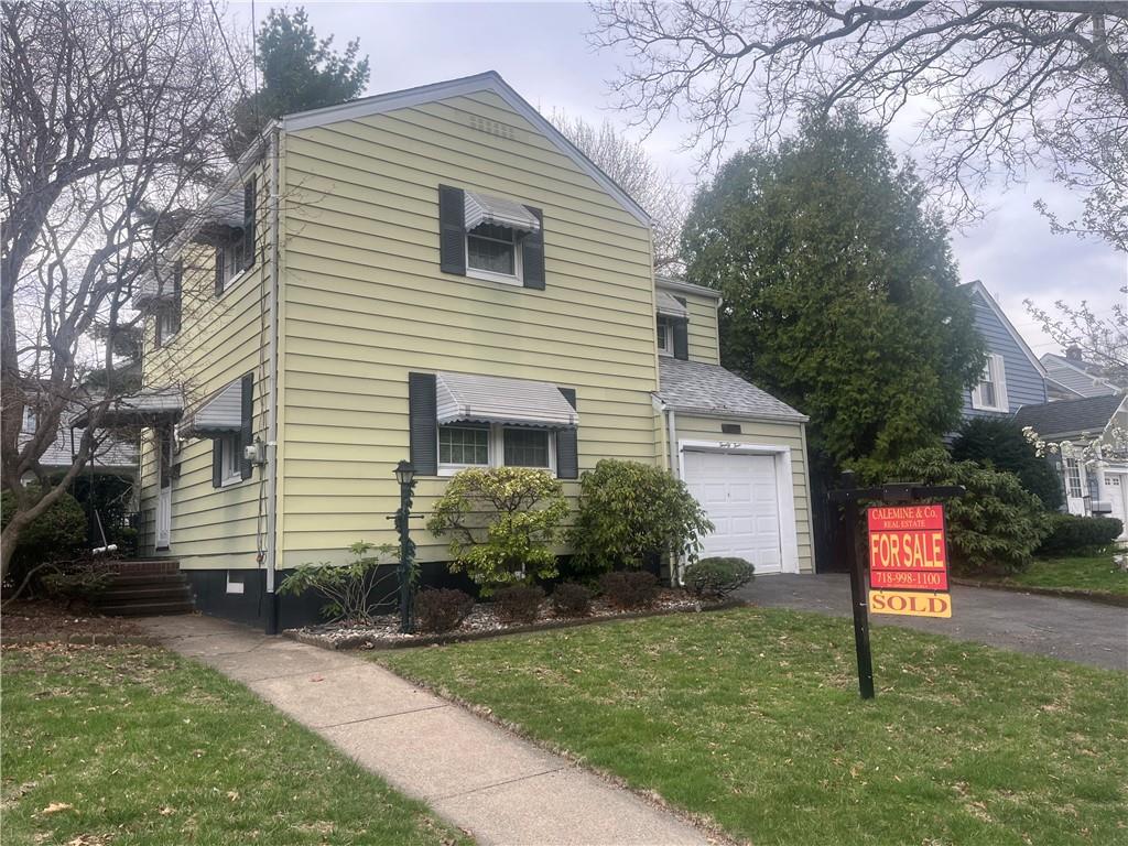 a front view of a house with a yard and tree