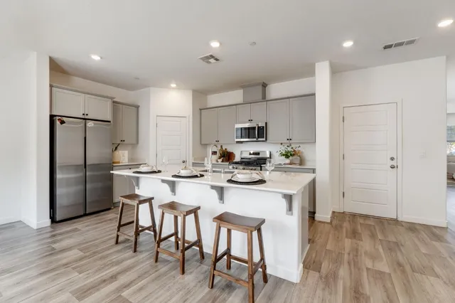 a kitchen with stainless steel appliances a table chairs refrigerator and microwave