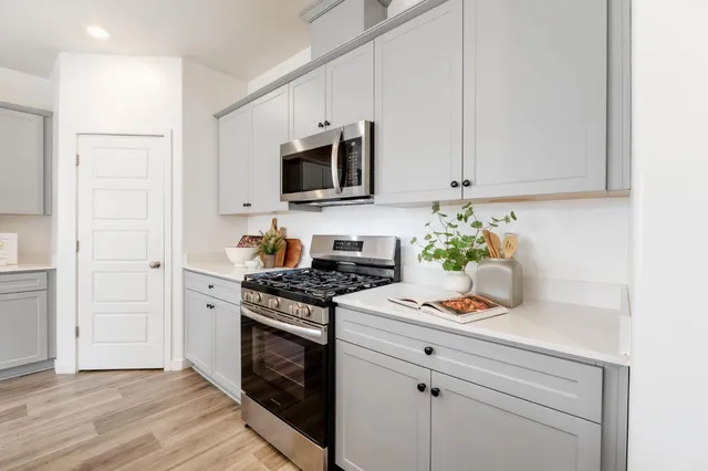 a kitchen with stainless steel appliances white cabinets and a stove top oven