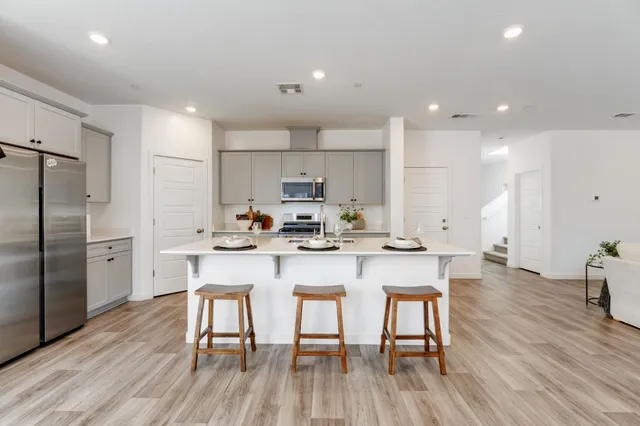 a kitchen with stainless steel appliances a table chairs refrigerator sink and cabinets
