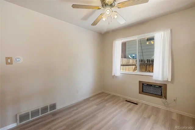 a view of an empty room with a window and wooden floor