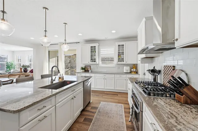 a kitchen with stainless steel appliances kitchen island granite countertop a sink a stove a refrigerator and island with wooden floor