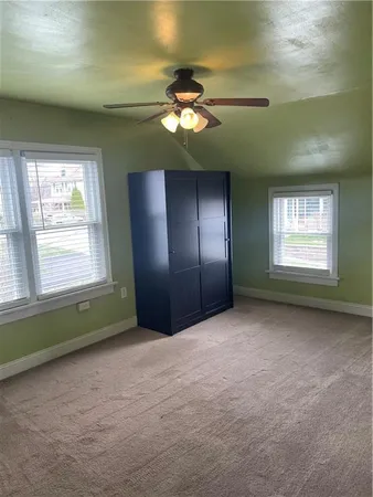 a view of an empty room with window and chandelier fan