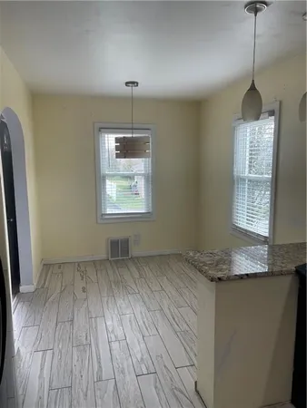 a view of an empty room with window and wooden floor
