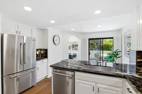 a kitchen with stainless steel appliances granite countertop a refrigerator a sink and wooden cabinets