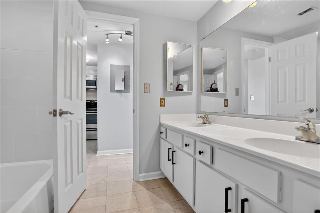 199 14th Street Northeast, Unit 711 Atlanta, GA 30309 - Photo 11 of 22 a spacious bathroom with a double vanity sink a mirror and a bathtub