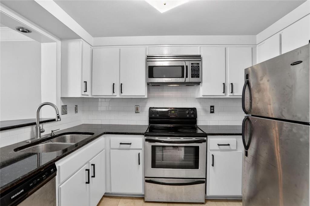 199 14th Street Northeast, Unit 711 Atlanta, GA 30309 - Photo 10 of 22 a kitchen with white cabinets and stainless steel appliances