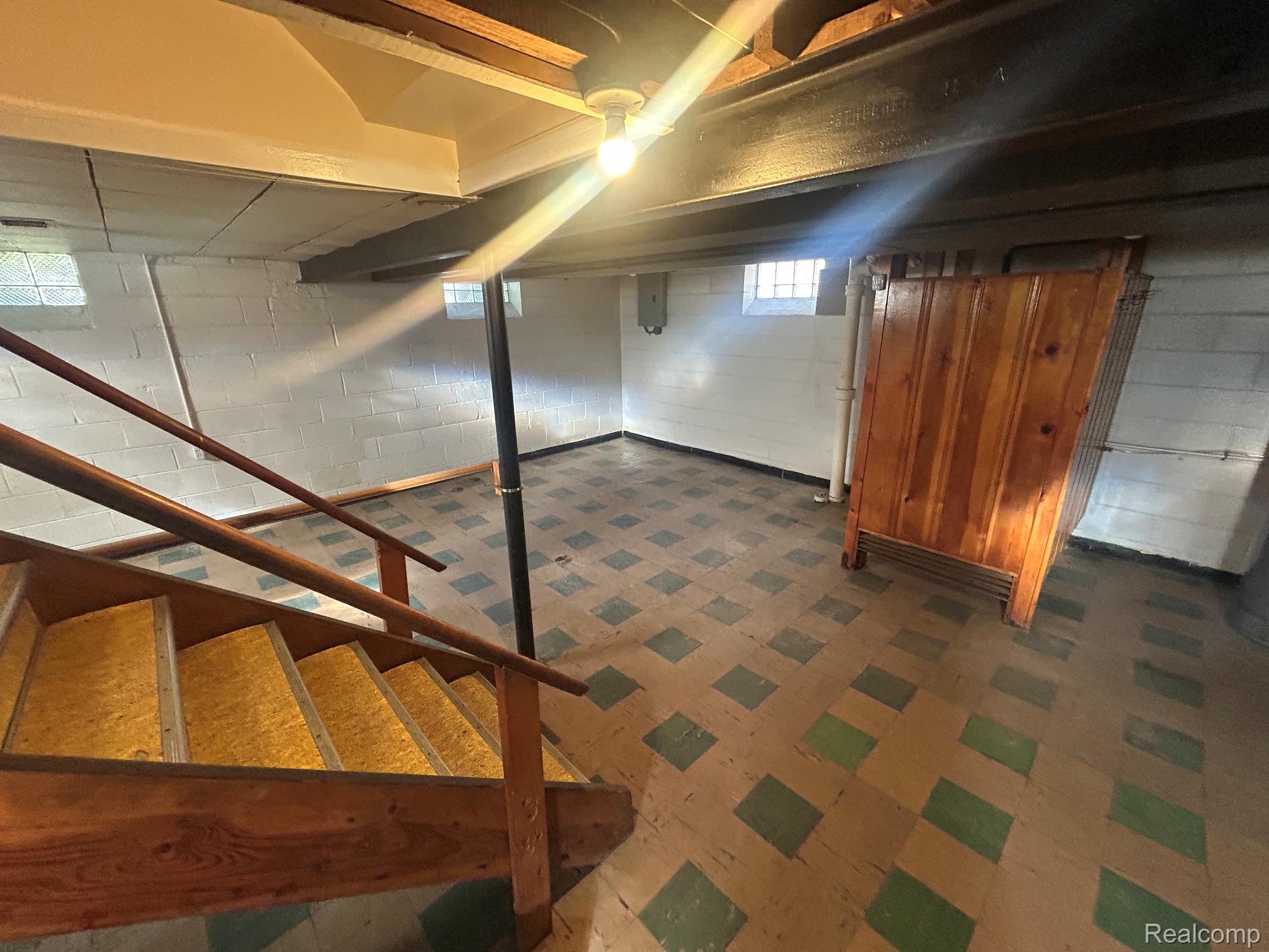 21970 Moross Road Grosse Pointe, MI 48236 - Photo 16 of 21 Expansive lower level featuring a patterned tile floor, painted brick walls, exposed ceiling beams, and a built-in wooden structure