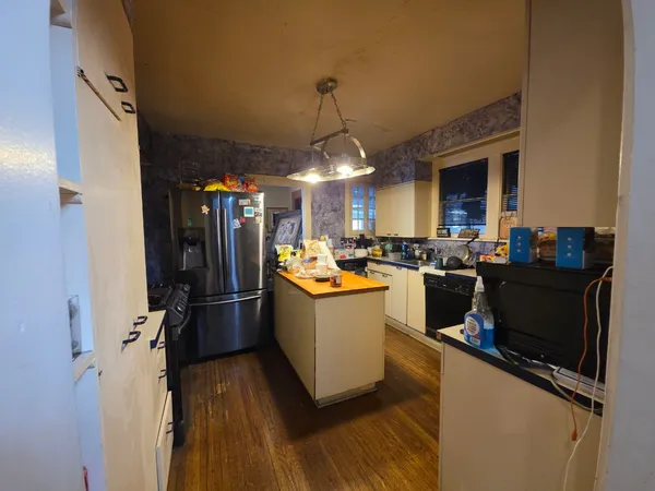 a kitchen view of a refrigerator and a wooden floor