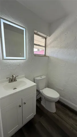 a bathroom with a toilet a sink a mirror and a window