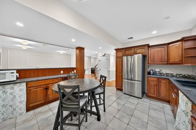 a kitchen with stainless steel appliances granite countertop a stove a sink a refrigerator with a dining table and chairs