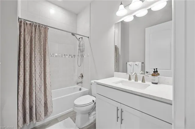 a bathroom with a sink a toilet a mirror a bathtub and shower