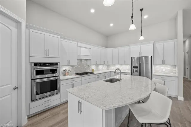 a kitchen with kitchen island a white counter top space cabinets and stainless steel appliances