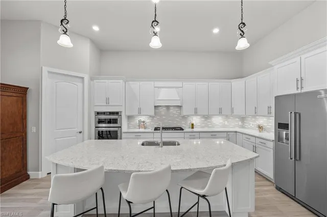 a kitchen with stainless steel appliances granite countertop a sink a stove a refrigerator cabinets and chairs